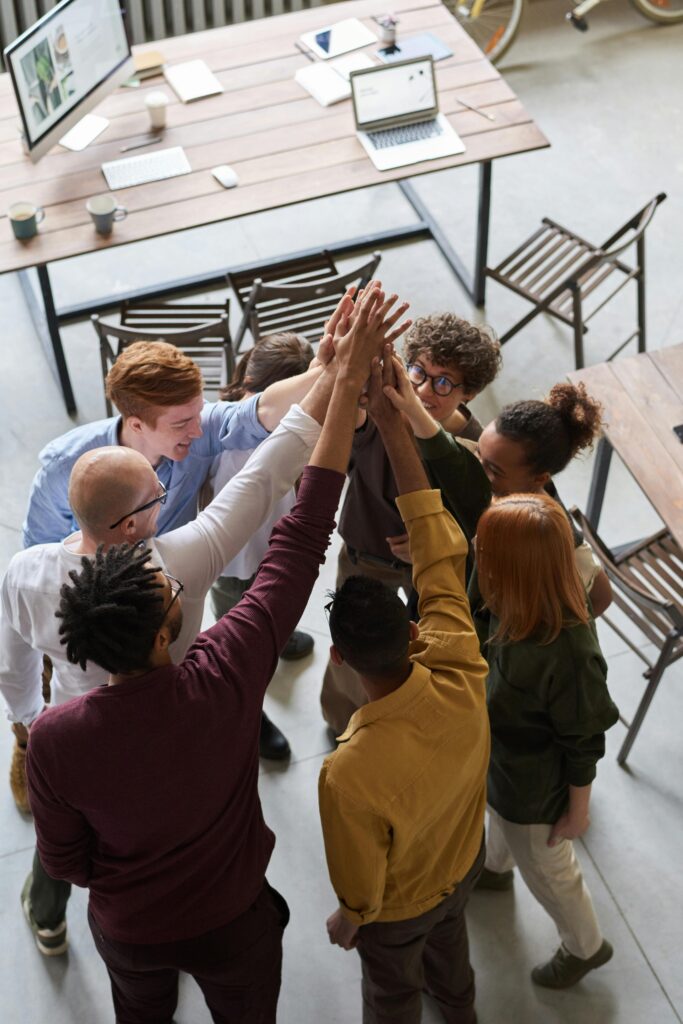 pexels-photo-3184433-3184433 A diverse group of professionals high-fiving in a modern office, showcasing teamwork and collaboration.